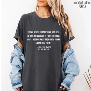 May include: Dark gray t-shirt with the quote "IF YOU BELIEVE IN SOMETHING, YOU NEED TO HAVE THE COURAGE TO FIGHT FOR THOSE IDEAS - NOT RUN AWAY FROM THEM OR TRY AND SILENCE THEM." by Charlie Kirk. The shirt is labeled "comfort colors PEPPER".