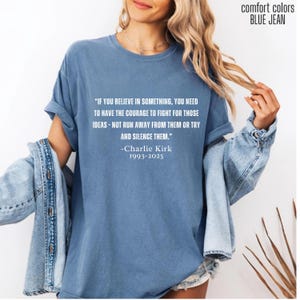 May include: Blue jean-colored t-shirt with the quote "IF YOU BELIEVE IN SOMETHING, YOU NEED TO HAVE THE COURAGE TO FIGHT FOR THOSE IDEAS - NOT RUN AWAY FROM THEM OR TRY AND SILENCE THEM." by Charlie Kirk, 1993-2025. The shirt is a comfort colors brand.