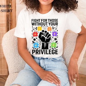 May include: White t-shirt with the text "FIGHT FOR THOSE WITHOUT YOUR PRIVILEGE" in black. The design includes a black fist surrounded by colorful flowers. The words "WHITE T-SHIRT" are in the upper left corner.