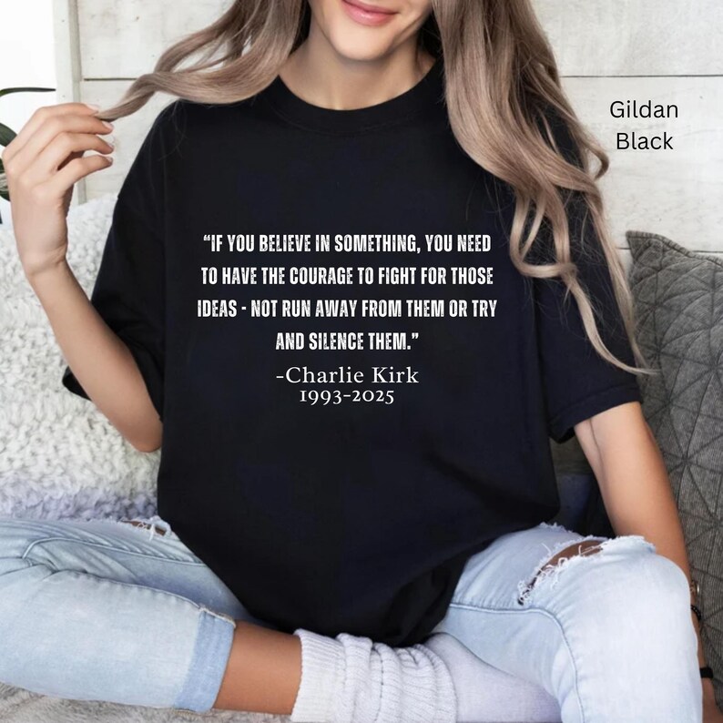 May include: Black Gildan t-shirt with a quote by Charlie Kirk: "IF YOU BELIEVE IN SOMETHING, YOU NEED TO HAVE THE COURAGE TO FIGHT FOR THOSE IDEAS - NOT RUN AWAY FROM THEM OR TRY AND SILENCE THEM." The quote is in white text.