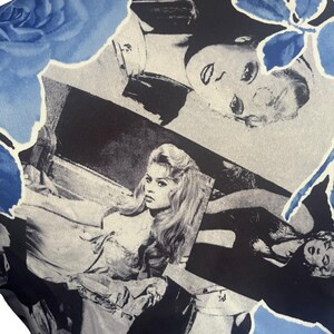 May include: A close-up of a garment with a repeating pattern of black and white celebrity portraits and blue floral accents. The fabric has a silky sheen and a light cream-colored neckline.