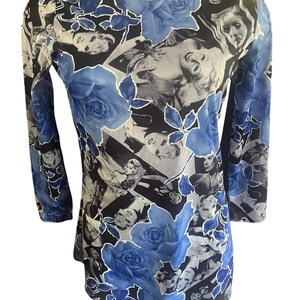 May include: Long-sleeved top with a unique design. The top features a pattern of black and white faces, blue roses, and a black background. The sleeves are three-quarter length, and the neckline is a scoop neck.