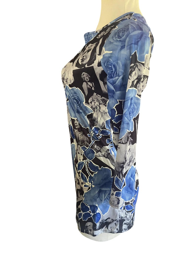 May include: Long-sleeved shirt with a unique design. The shirt features a collage of black and white images of a woman, with large blue rose illustrations. The shirt has a round neckline and a fitted silhouette.