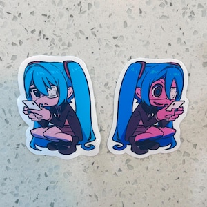 May include: Two stickers featuring a cartoon character with long blue pigtails, wearing glasses and a black jacket, engrossed in a smartphone. The character is depicted in a seated position with a pink complexion.