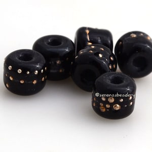 May include: Six black glass beads with gold dots. The beads are round and have a hole in the center. They are perfect for jewelry making.