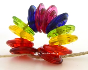 May include: A rainbow of colorful glass buttons strung on a piece of twine. The buttons are stacked in a circle, with the colors red, orange, yellow, green, blue, and purple.