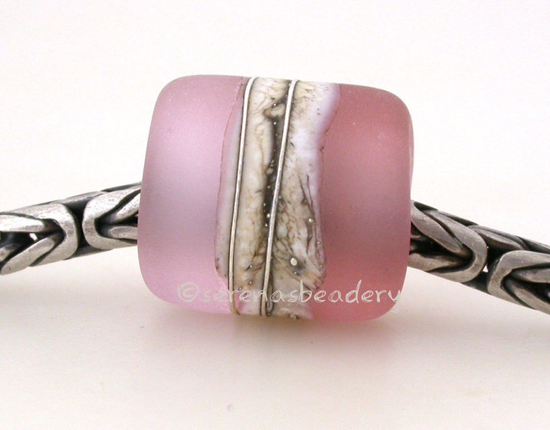 May include: A pink glass bead with a white and brown marbled design. The bead is on a silver chain.