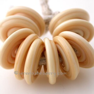 May include: A strand of cream-colored glass beads with a swirling pattern. The beads are round and have a smooth, glossy finish.