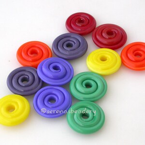 K&ouml;nnte beinhalten: Sortiment an bunten Glasperlen mit Spiraldesign. Die Perlen sind in den Farben Rot, Orange, Gelb, Gr&uuml;n, Blau und Lila.