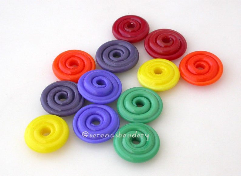 K&ouml;nnte beinhalten: Sortiment an bunten Glasperlen mit Spiraldesign. Die Perlen sind in den Farben Rot, Orange, Gelb, Gr&uuml;n, Blau und Lila.