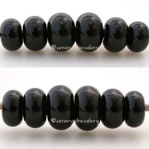 May include: Two rows of black round beads strung on a white cord. The beads are smooth and shiny.