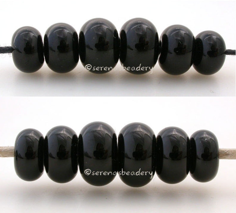 May include: Two rows of black round beads strung on a white cord. The beads are smooth and shiny.