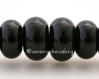 May include: A strand of six black glass beads, each with a slightly different shade of black, strung on a white cord.