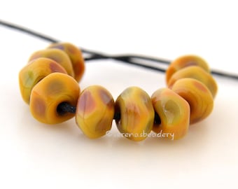 May include: A strand of eight yellow and brown glass beads with a mottled pattern. The beads are strung on a black cord.