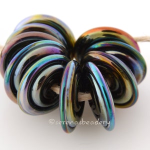 May include: A stack of iridescent black glass beads with a rainbow sheen. The beads are arranged in a spiral shape.