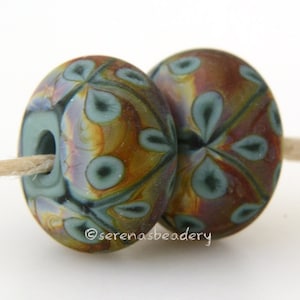 May include: Two glass beads with a swirling pattern of blue, brown, and gold. The beads have a hole in the center for stringing.