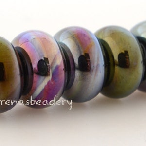 May include: Five iridescent glass beads with a dark green, blue, and purple color shift. The beads are strung on a white thread.