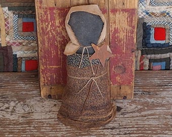 Muñeca primitiva negra de la pradera con vestido de calico de reproducción y delantal desgastado con broche de estrella oxidada.