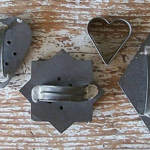 Close-up of the back side of 4 antique or very vintage cookie cutters with soldered handles.