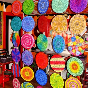 May include: A wall decoration made of colourful round discs with intricate mandala designs. The discs are suspended from the ceiling and hang in a staggered pattern.
