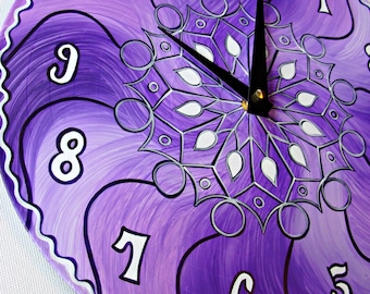 May include: Purple and white clock with a mandala design. The clock face has black hands and white numbers.