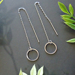 May include: A pair of silver chain earrings with a small circle pendant at the end of each chain.