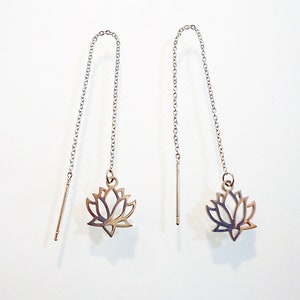 May include: A pair of silver dangle earrings with a lotus flower design. The earrings are made of a thin chain and have a simple, elegant look.