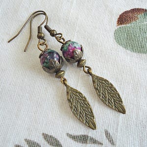 May include: A pair of bronze earrings with green and pink gemstone beads and leaf-shaped dangles.