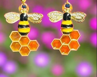 May include: A pair of gold bee earrings with clear rhinestones and orange honeycomb accents.