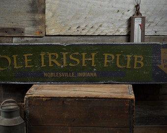 Può includere: Un cartello di legno dipinto di verde e nero. Il cartello recita "Ole Irish Pub" in lettere dorate con le parole "Noblesville, Indiana" sotto. Il cartello ha anche una freccia nera che punta verso il basso con le parole "Enter Here" in lettere dorate.