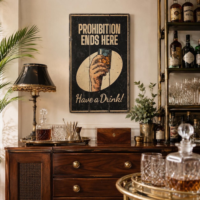 May include: A rectangular wall sign with a black background featuring the text PROHIBITION ENDS HERE and Have a Drink! in cream-colored lettering. The center displays a graphic of a hand holding a glass of amber liquid inside a cream oval.