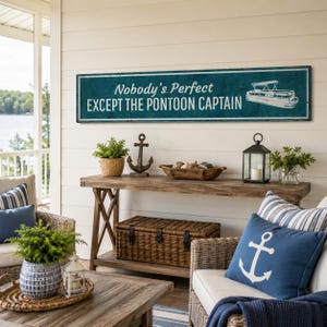 Op de afbeelding: Een rechthoekig wandbord met een groenblauwe achtergrond en witte tekst die Nobody's Perfect EXCEPT THE PONTOON CAPTAIN leest, met een witte lijntekening van een pontonboot aan de rechterkant en een dunne witte rand rondom.