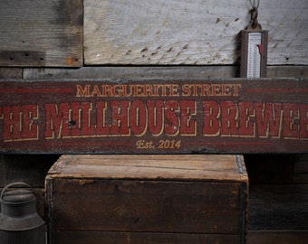 May include: A rustic wooden sign with red and yellow lettering that reads "Marguerite Street The Millhouse Brewery Est. 2014".