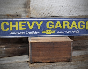 Può includere: Un cartello blu e giallo con il testo "CHEVY GARAGE" in lettere gialle. Il cartello include anche il testo "American Tradition" e "American Pride" in lettere bianche. Il logo Chevrolet è anche visibile sul cartello.