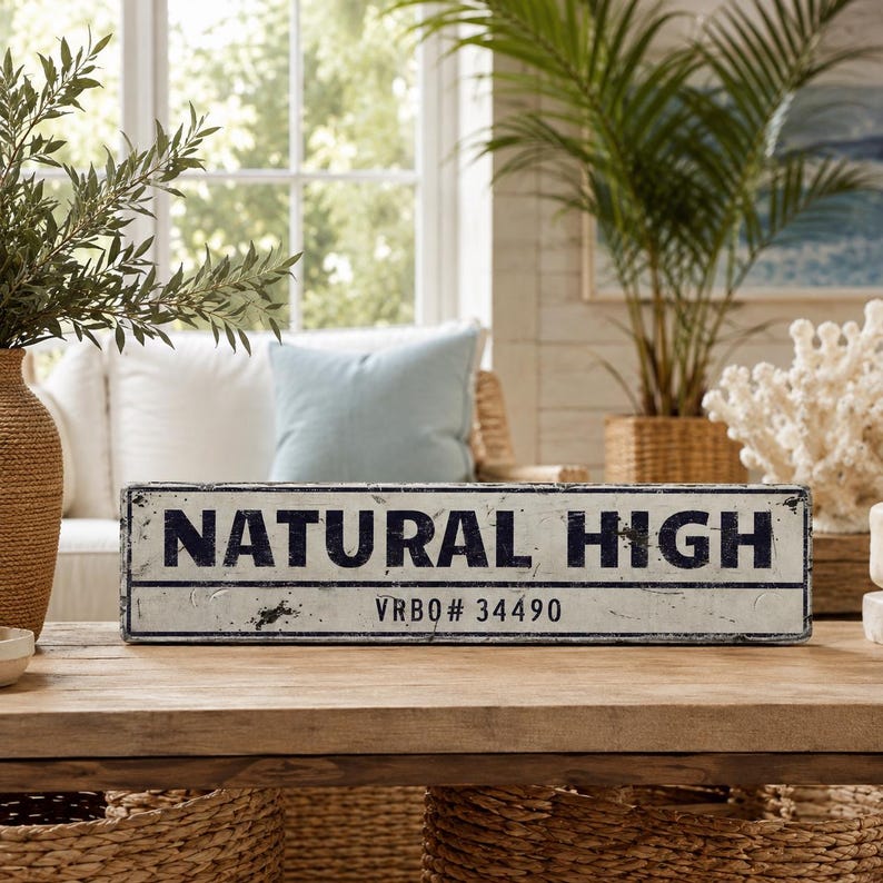 May include: A rectangular white sign with a distressed finish and black border. The text "NATURAL HIGH" is printed in large, bold, black capital letters, with "VRBO# 34490" printed in smaller black text centered underneath the main line.
