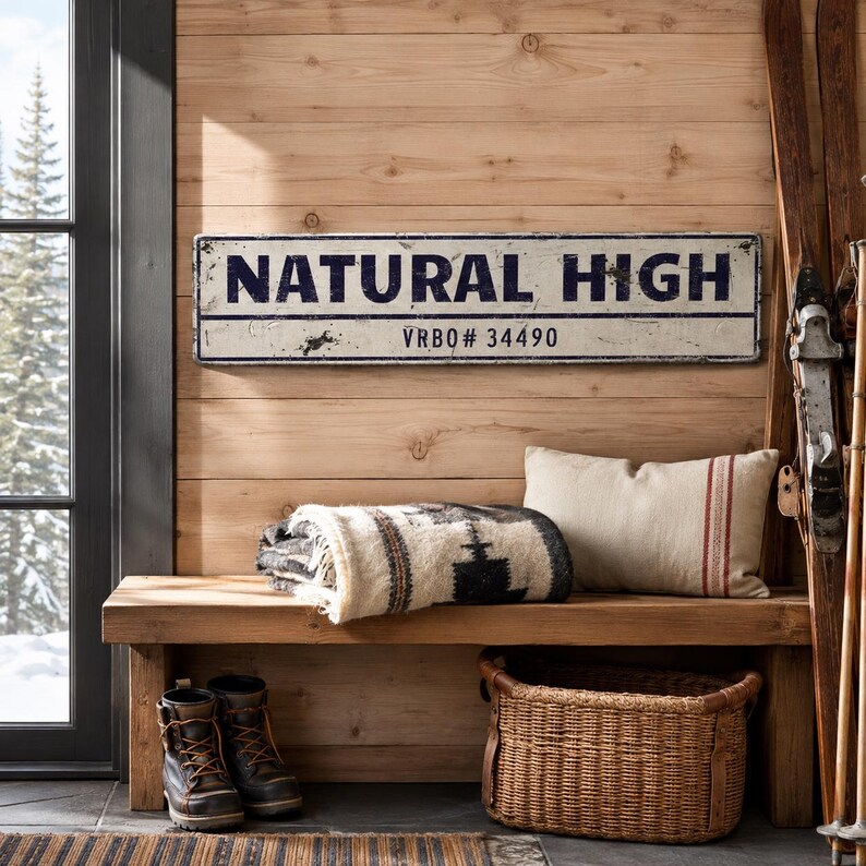 May include: A rectangular white metal sign with a distressed finish featuring the dark blue text NATURAL HIGH and the smaller text VRB0# 34490. The sign has a thin dark blue horizontal line separating the two lines of text.