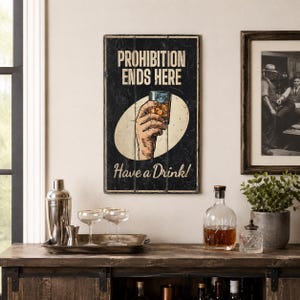 May include: A rectangular wall sign with a black background featuring the text PROHIBITION ENDS HERE and Have a Drink! in white and cream lettering. A central illustration shows a hand holding a glass of amber liquid inside a cream oval.