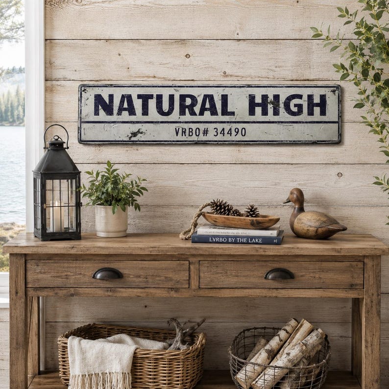 May include: A rectangular metal sign with a distressed white finish and black border. The text "NATURAL HIGH" is printed in large, bold, dark blue capital letters, with "VRBO# 34490" printed in smaller black text on a horizontal line below.