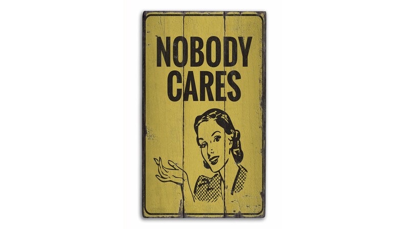 May include: A yellow wooden sign with black text that reads "Nobody Cares". A vintage-style illustration of a woman with a surprised expression is below the text.