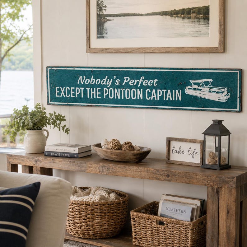 Op de afbeelding: Een lang, rechthoekig metalen bord in een blauwgroene kleur met een verweerde afwerking. Het bord bevat witte tekst met de tekst "Nobody's Perfect EXCEPT THE PONTOON CAPTAIN" en een witte lijntekening van een pontonboot aan de rechterkant.
