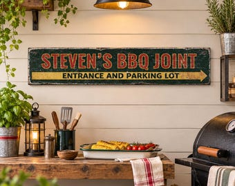 May include: A rectangular horizontal sign with a dark green background and a distressed finish. The text reads STEVEN'S BBQ JOINT in large red letters, with ENTRANCE AND PARKING LOT in black on a yellow arrow pointing to the right.