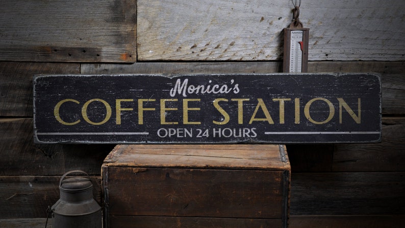 Może przedstawiać: Czarny drewniany znak z białymi i złotymi literami, na kt&oacute;rym widnieje napis "Monica's Coffee Station Open 24 Hours".