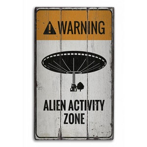 May include: A white wooden sign with black text and a black silhouette of a UFO. The sign reads "WARNING ALIEN ACTIVITY ZONE".