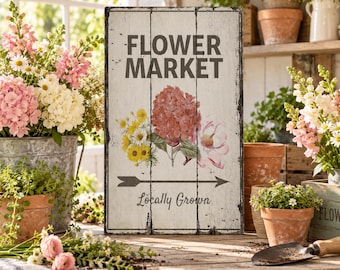 May include: A rectangular wooden sign with a distressed white finish featuring the dark gray text FLOWER MARKET and LOCALLY GROWN. The center displays a botanical illustration of a red hydrangea, yellow daisies, and a pink flower above an arrow.