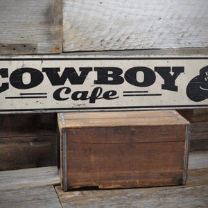 a cowboy cafe sign on a wooden wall