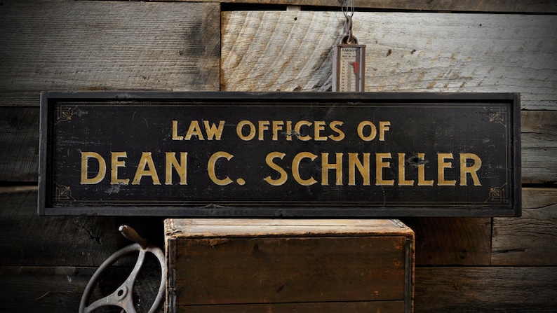 May include: Black wooden sign with gold lettering that reads "Law Offices of Dean C. Schneller".