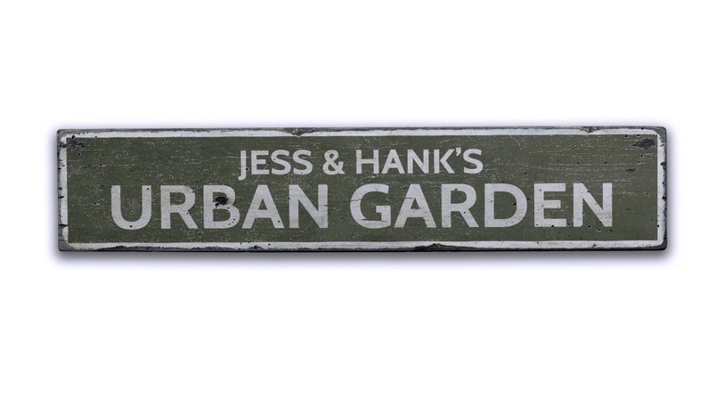 May include: A weathered green wooden sign with white lettering that reads "Jess & Hank's Urban Garden".