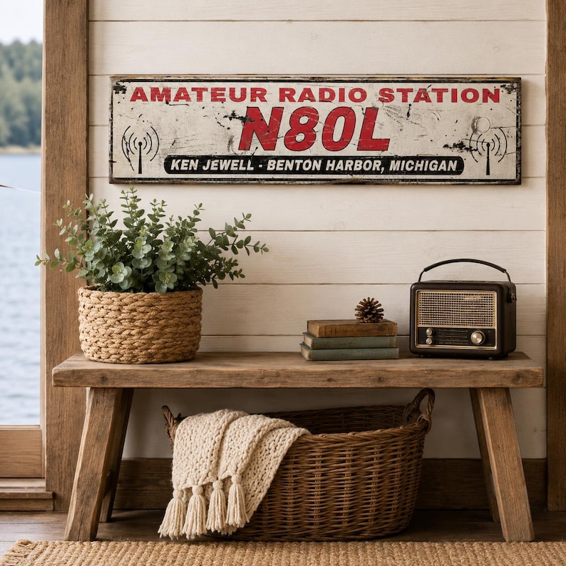 May include: A rectangular metal sign with a distressed white finish, featuring the red text AMATEUR RADIO STATION, the call sign N80L in large red letters, and the black text KEN JEWELL - BENTON HARBOR, MICHIGAN, along with black radio tower icons.