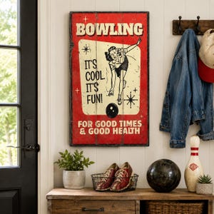 May include: A rectangular wall sign with a red background and a cream-coloured centre panel featuring a black illustration of a person bowling. The text reads BOWLING IT'S COOL. IT'S FUN! FOR GOOD TIMES & GOOD HEALTH in black and white lettering.