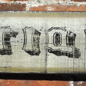 Op de afbeelding: Een verweerd houten bord met het woord "ANTIQUES" in zwarte letters.